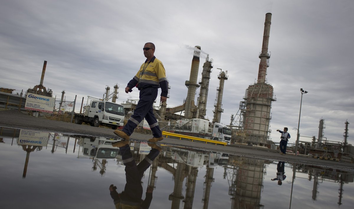 A worker is reflected in a puddle at Sydney's Caltex Oil refinery after the completion of shutting down of the refinery and its transition to an oil storage facility, in Kurnell