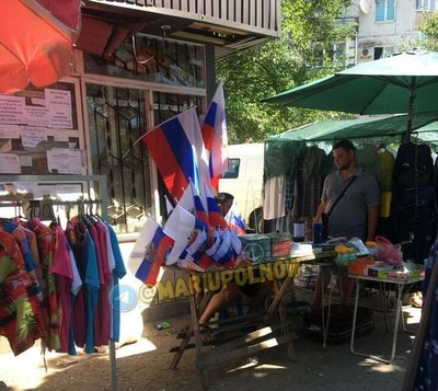 В Мариуполе на середину июля 2022 года еще закрыты магазины, где можно было бы купить одежду, технику, предметы быта. Что-то продают на рынках вместе с российскими флагами