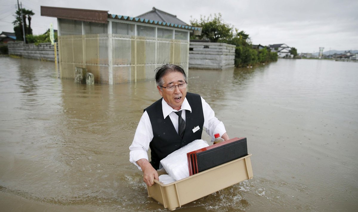 A man holding a tray of belongings wades through a road at an area flooded by the Omoigawa river, caused by typhoon Etau in Oyama