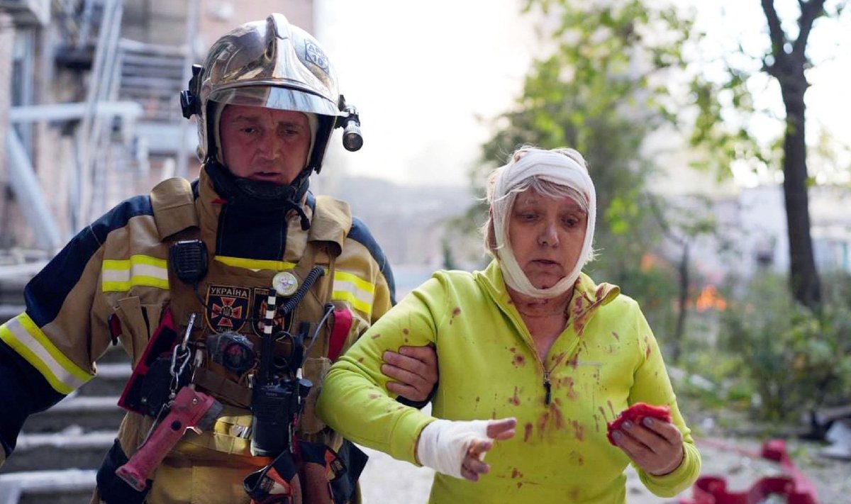 Спасатель помогает женщине, пострадавшей из-за обстрелов Киева 10-го октября.