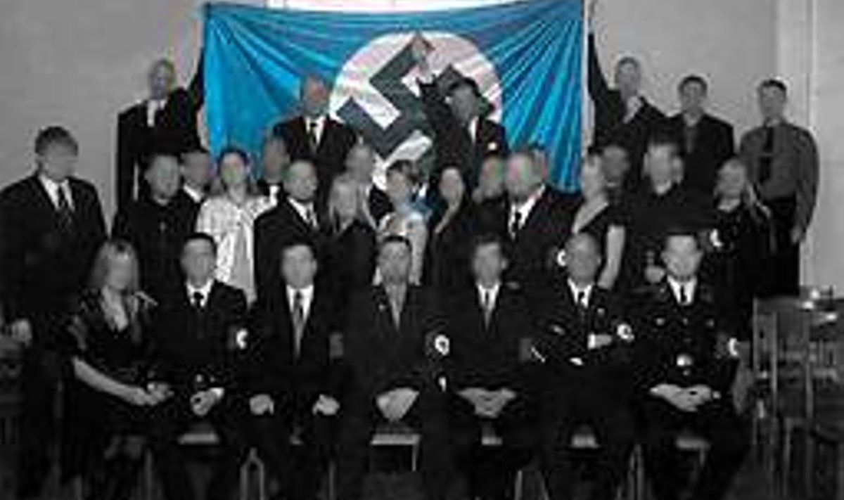 30 inimest poseerib Adolf Hitleri sünniaasta­päeval 2007 sinimustvalge haak­ristilipu all, kuigi osa neist ei saanud aru, mida see lipp tähendab. Pildid Teinoneni veebiküljelt, kus ta on osalejate näod kinni katnud. www.kaitsepolitsei.com