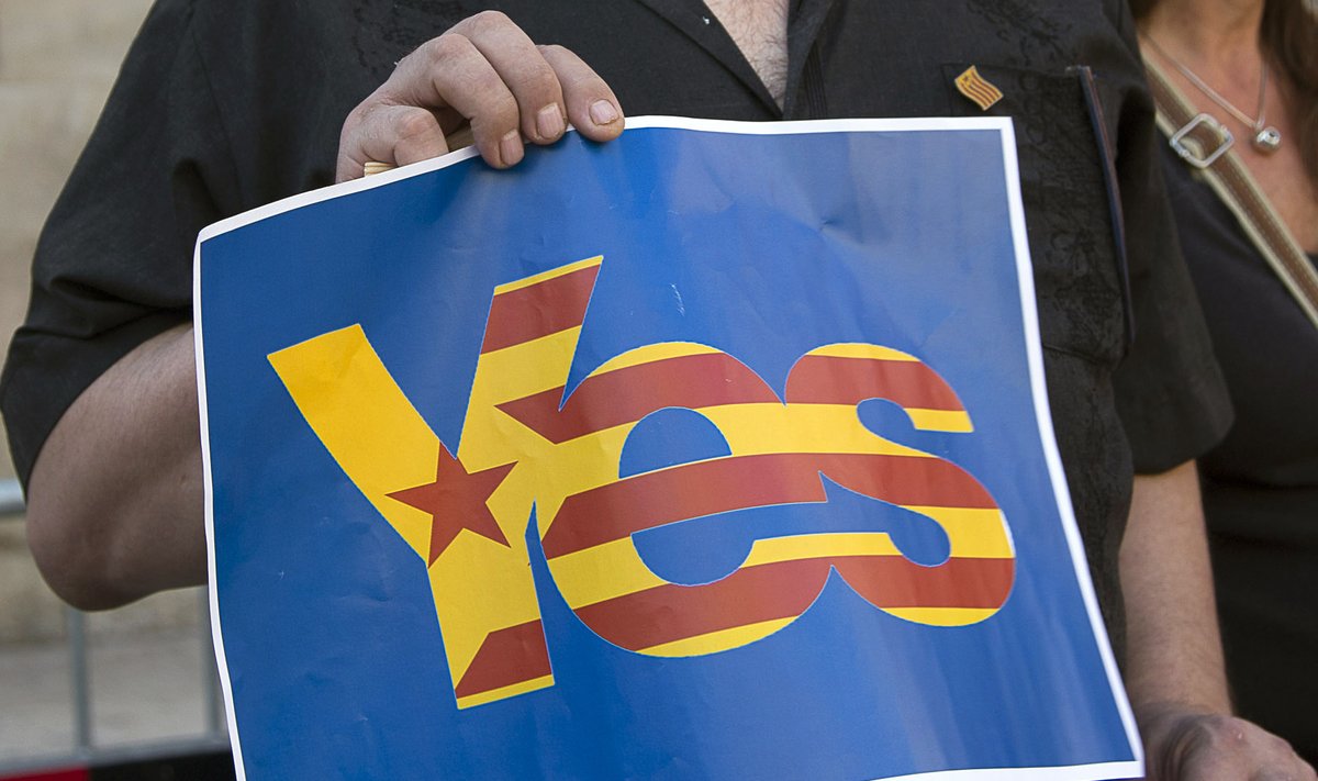 Catalunya's separatist supporters hold a sign supporting Scotland's independence as they wave Esteladas (Catalan separatist flags) at Sant Jaume square in Barcelona