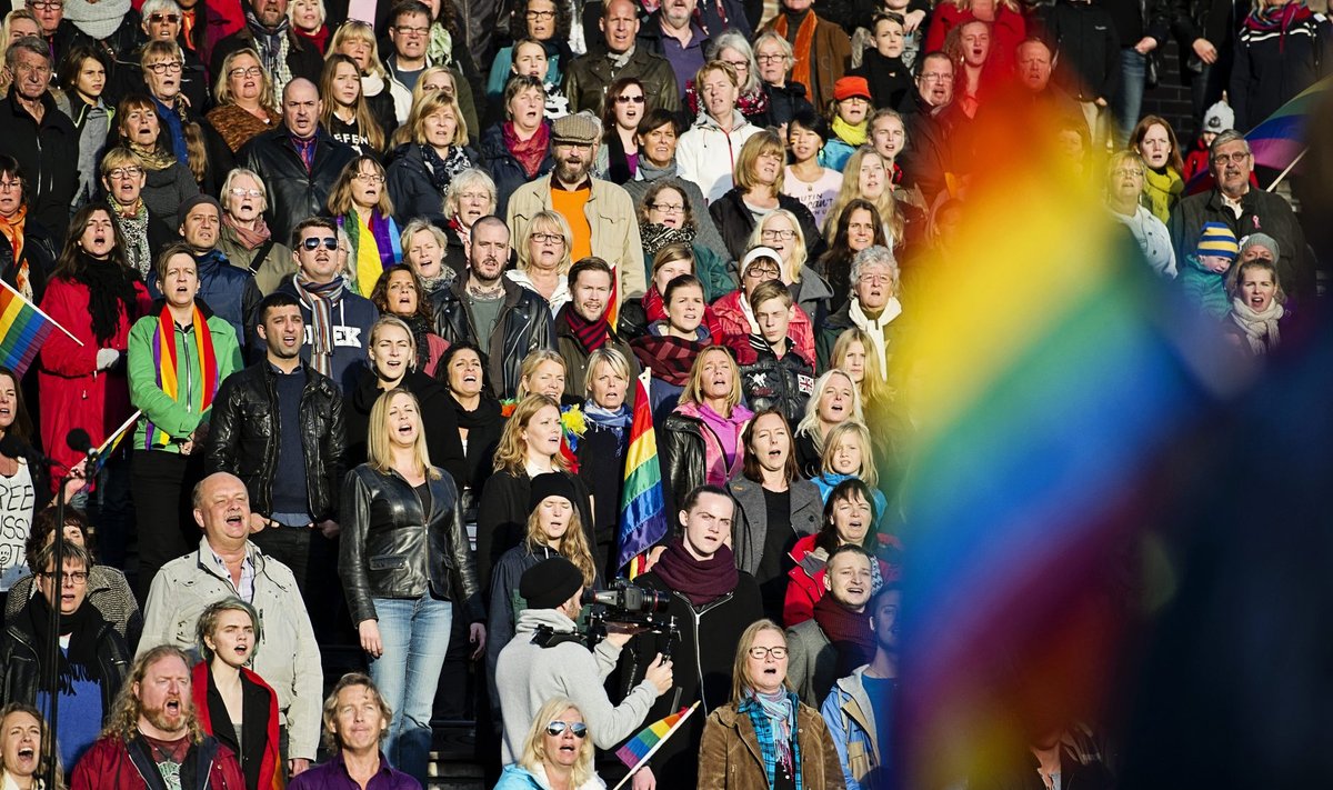 People sing the Russian national anthem while raising rainbow flags at the Stockholm Olympic Stadium