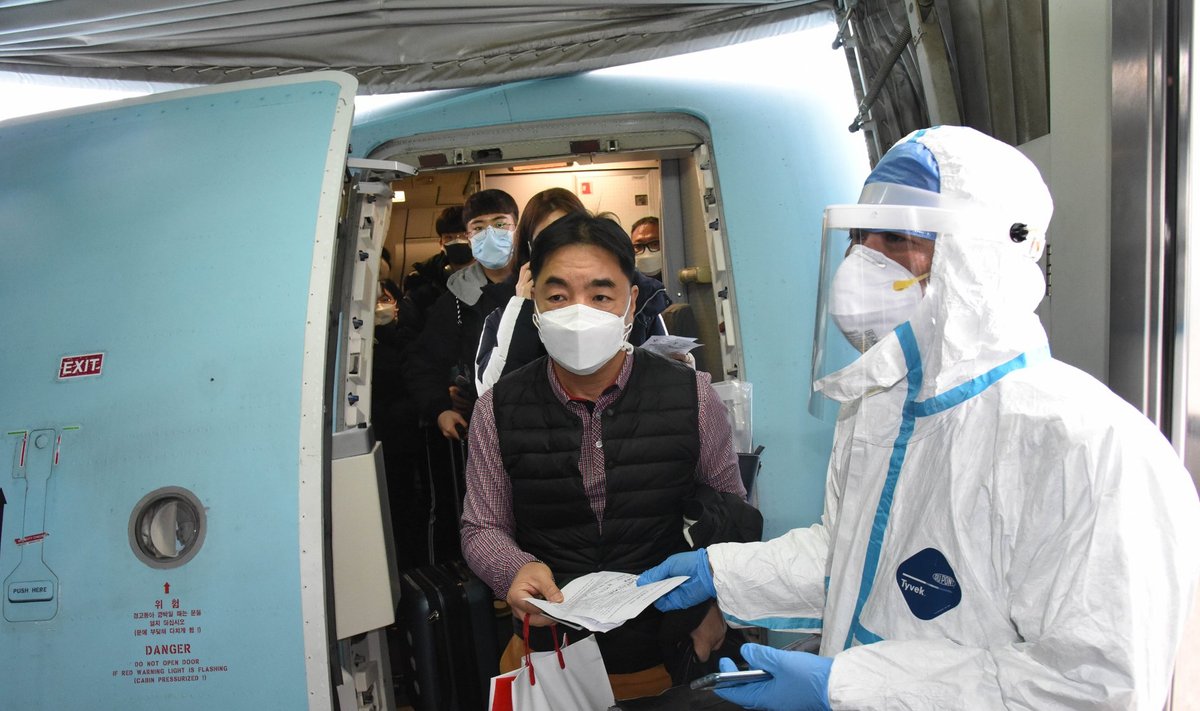 TÄIELIK KONTROLL: Reisijad väljuvad meditsiinitöötaja valvsa pilgu all Qingdao lennujaamas lennukist.