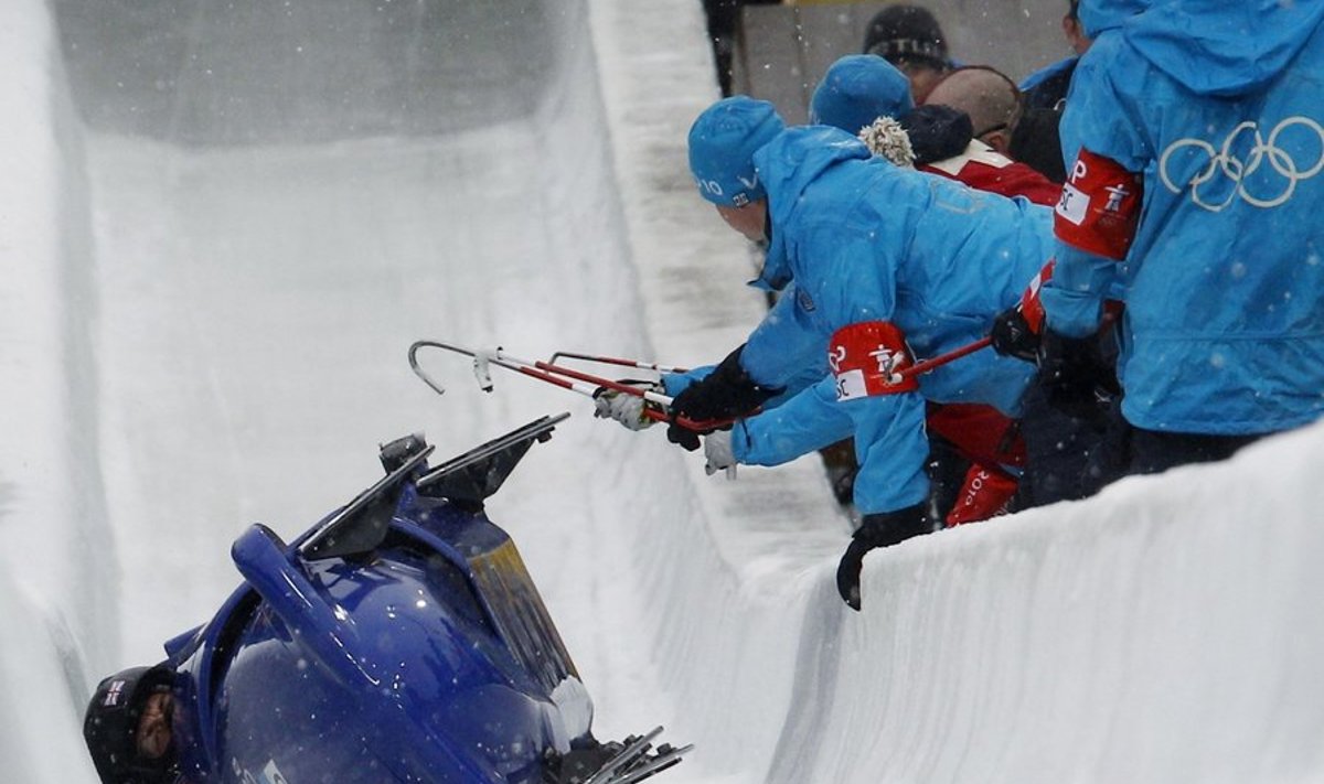 Pilot John Jackson, Henry Odili Nwume, Dan Money and Allyn Condon of team Britain 1 are assisted by track staff after they crashed during heat 2 of the four-man bobsleigh competition at the Vancouver 2010 Winter Olympics in Whistler, British Columbia, February 26, 2010.     REUTERS/Jim Young (CANADA)