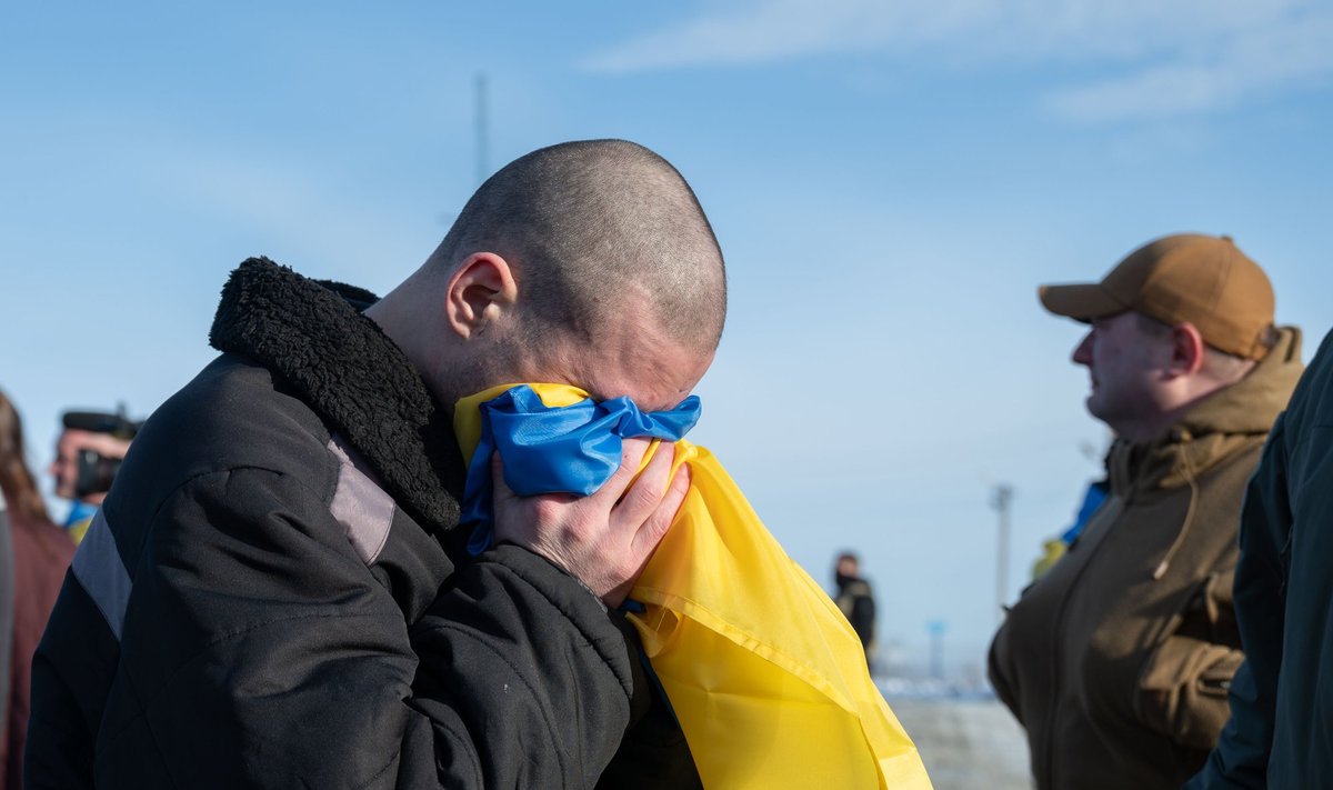 Украинский солдат плачет в флаг Украины, вернувшись домой после обмена военнопленными между Россией и Украиной, 31 января 2024 года