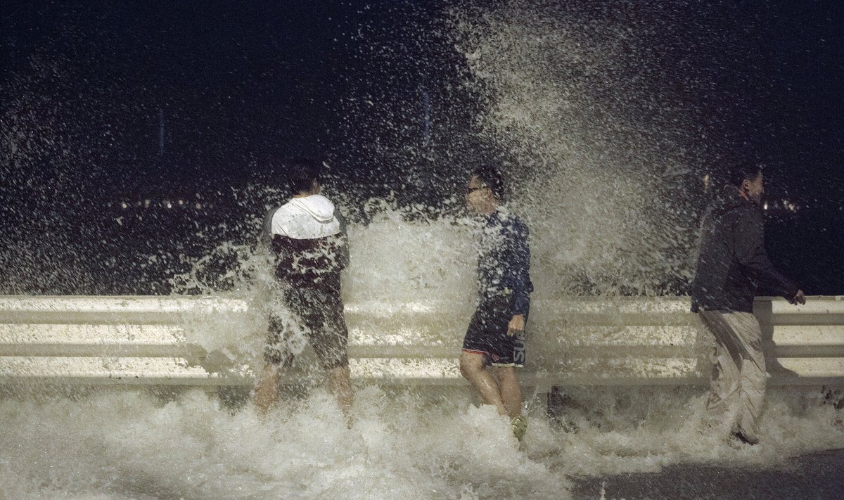 People react as waves splash on to the road during Typhoon Usagi in Hong Kong