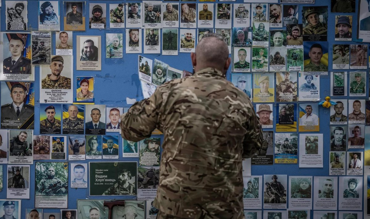 Украинский военный размещает фотографию погибшего на фронте товарища на Стене памяти возле здания МИД Украины