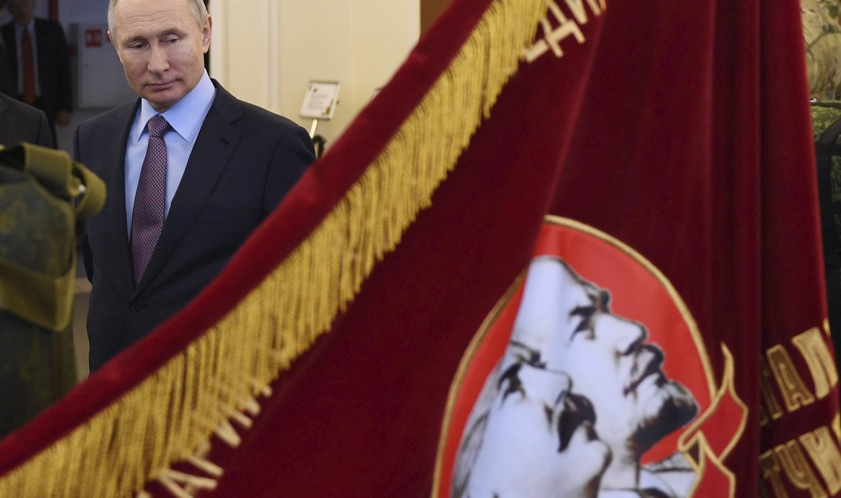 Президент России Владимир Путин смотрит на советское знамя с изображением Владимира Ленина и Иосифа Сталина.