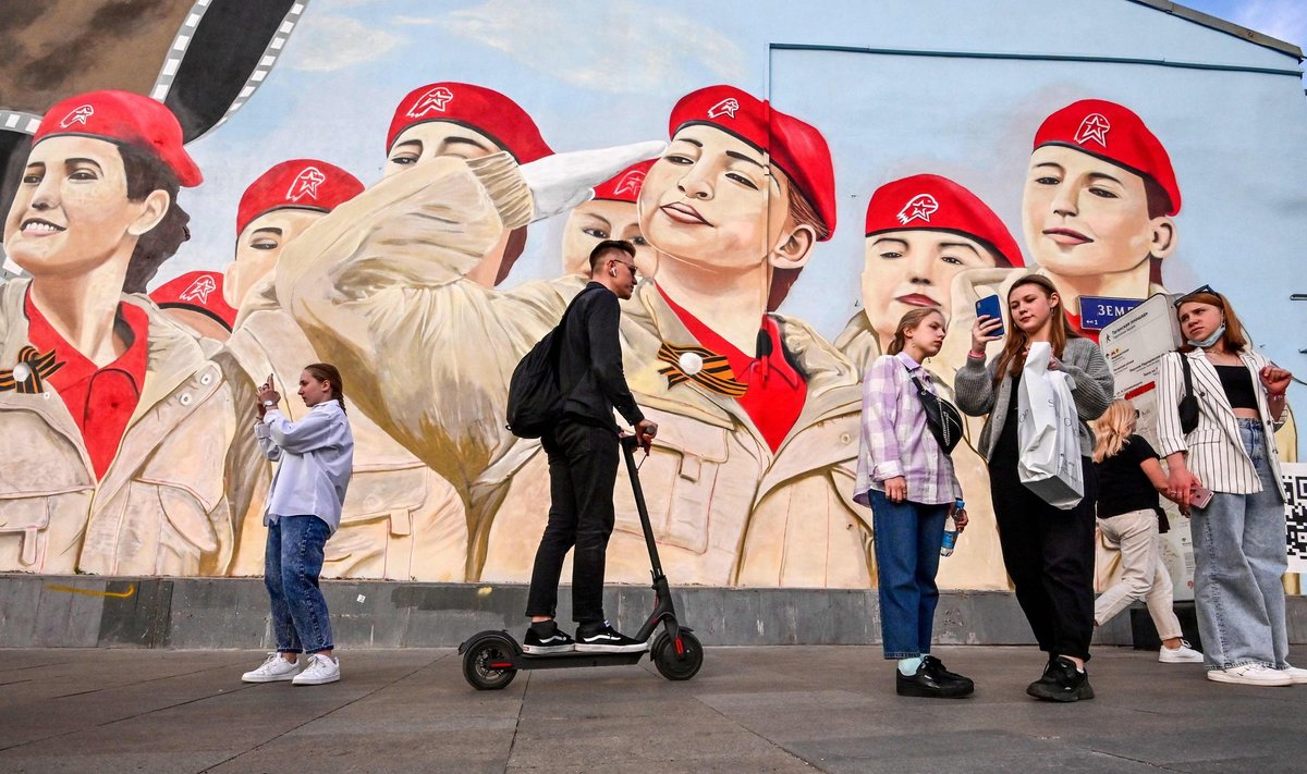 Kremli üks suurimaid muresid enne sügisesi valimisi on küsimus, kuidas saada inimesed hääletama. Pildil on Moskva elanikud sõjalis-patriootlikku noorteliikumist Junarmija kujutava seinamaali taustal.