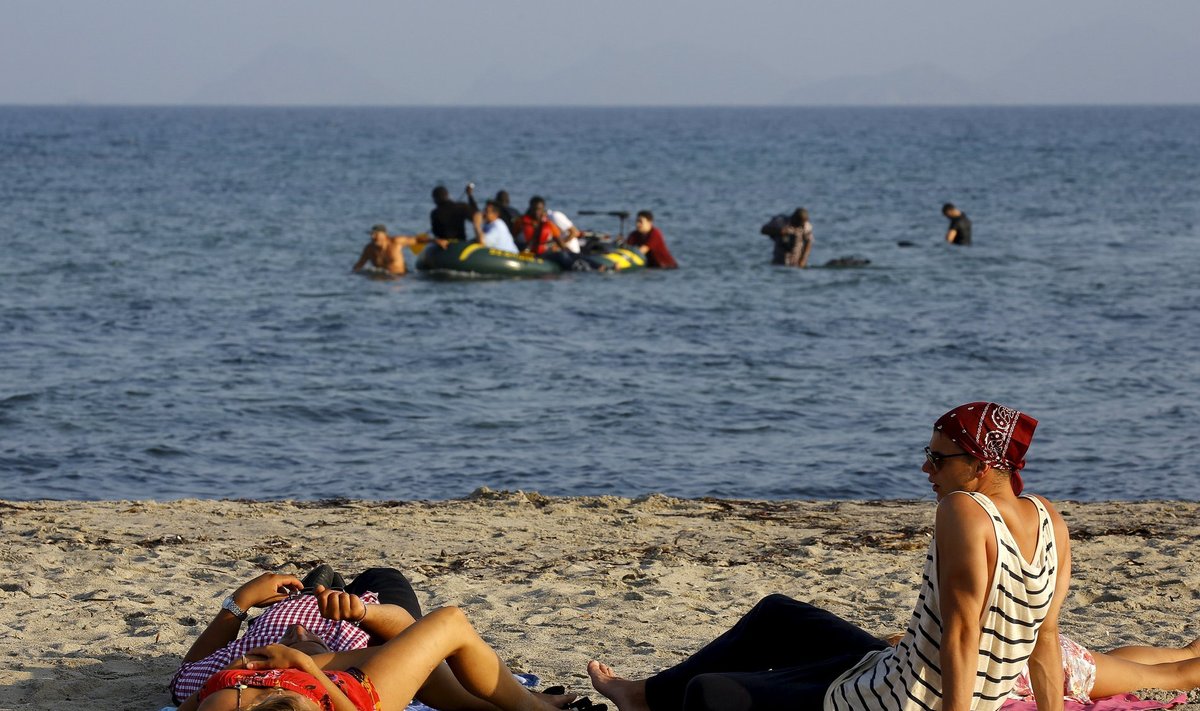 Päikest võtvad turistid vaatavad Kreekas Kosi saarel, kuidas saabub järjekordne paatkond põgenikke.