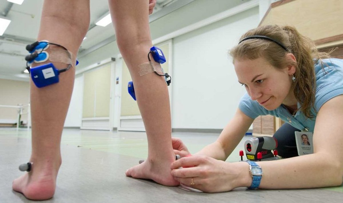 Füsioterapeut Mari Alvelal kulub ligi tund, et kinnitada Toomase jalgadele kõik kõnnianalüüsiks vajalikud antennid ja andurid. (Foto: Rauno Volmar)