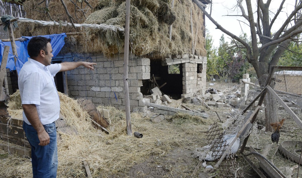 Мужчина показывает дом, поврежденный во время нового витка нагорно-карабахского конфликта между Азербайджаном и Арменией