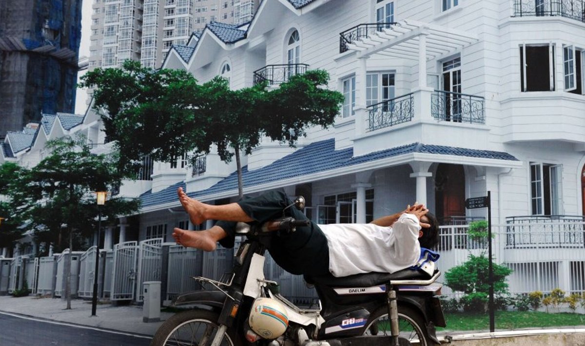 Mototakso juht  Ho Chi Minhi linnas kinnisvara reklaamplakati ees magamas.