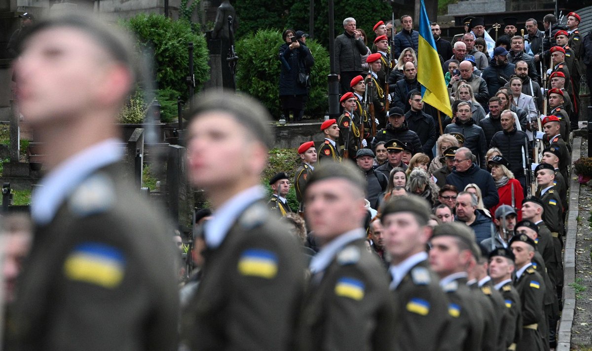 1 октября в Украине отмечают День защитников и защитниц. На фото - люди проходят мимо украинского почетного караула, чтобы посетить могилы украинских солдат на Лычаковском кладбище во Львове. 1 октября 2024 года.