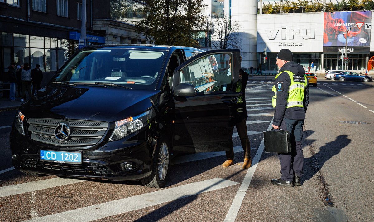  Diplomaati vedanud ja eraldusribal parkinud auto juht viitab parkimiskellale kui võluvõtmele.