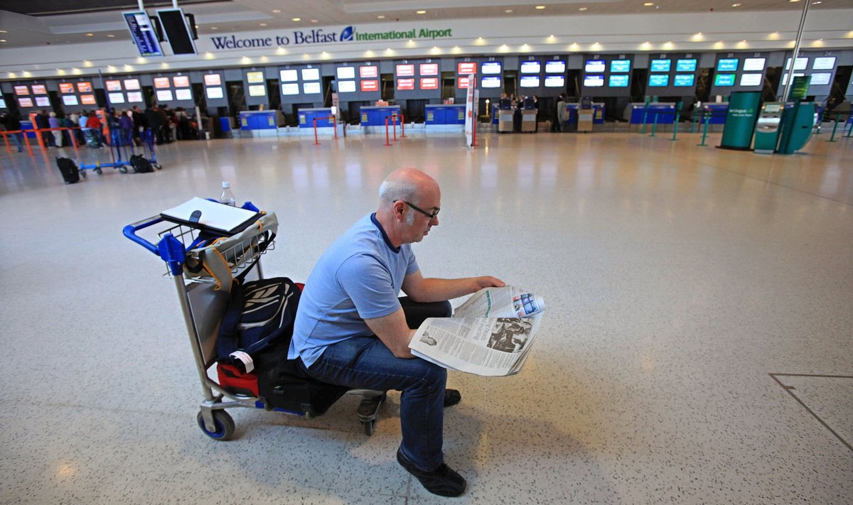 An airline passenger reads a newspaper beside empty Check-In counters at Belfast International airport in Northern Ireland, on April 15, 2010, following the closure of the airport due to a cloud of volcanic ash from Iceland. All London flights, including those from Heathrow, will be suspended from 1100 GMT Thursday due to volcanic ash from Iceland that has already caused almost 300 cancellations here, officials said. "All flights in and out of Heathrow and Stansted will be suspended from midday but the terminals will remain open," a spokeswoman for airports operator said. AFP PHOTO/PETER MUHLY