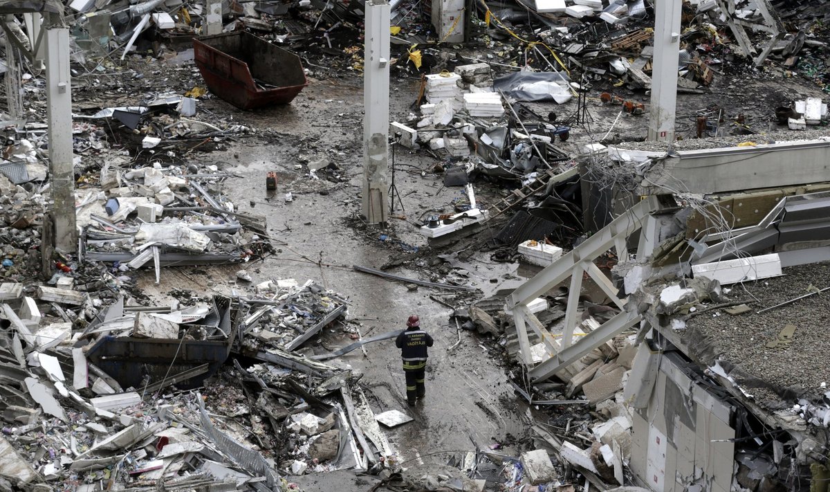 A rescue worker walks past debris of a collapsed supermarket in Riga