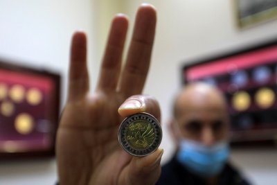 Мужчина демонстрирует монету египетского фунта в Музее монетного двора.