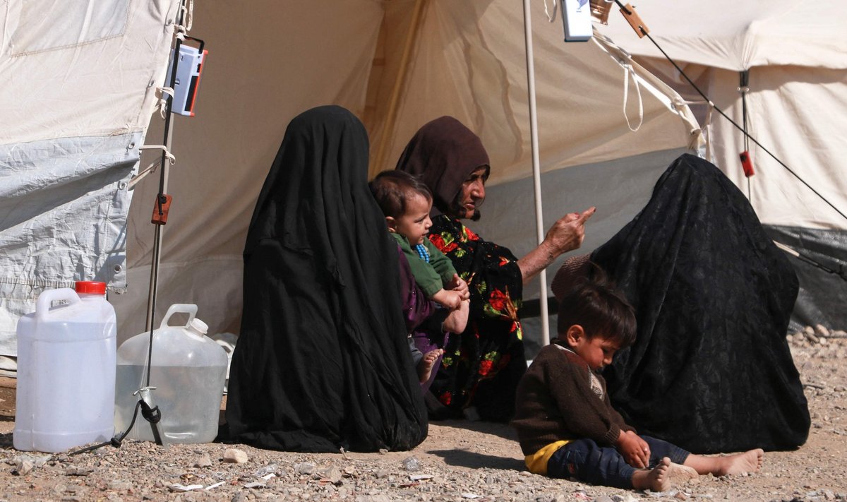 Афганские женщины и дети сидят перед своими временными убежищами