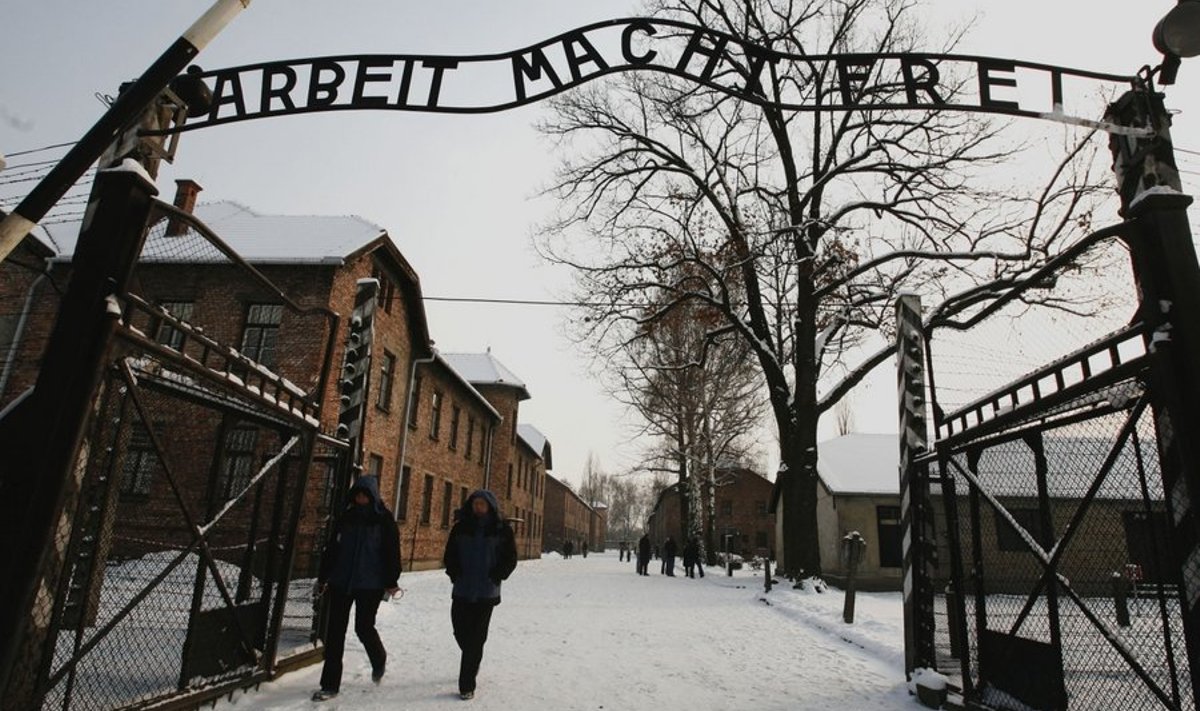 Tourists walk underneath the replacement of the sign "Arbeit macht frei" (work will set you free) in Auschwitz, Oswiecim, December 18, 2009. The notorious metal sign hanging at the entrance of the former Nazi death camp of Auschwitz that reads "Arbeit macht frei" was stolen on Friday, officials said. REUTERS/Irek Dorozanski (POLAND - Tags: ANNIVERSARY CRIME LAW IMAGES OF THE DAY)