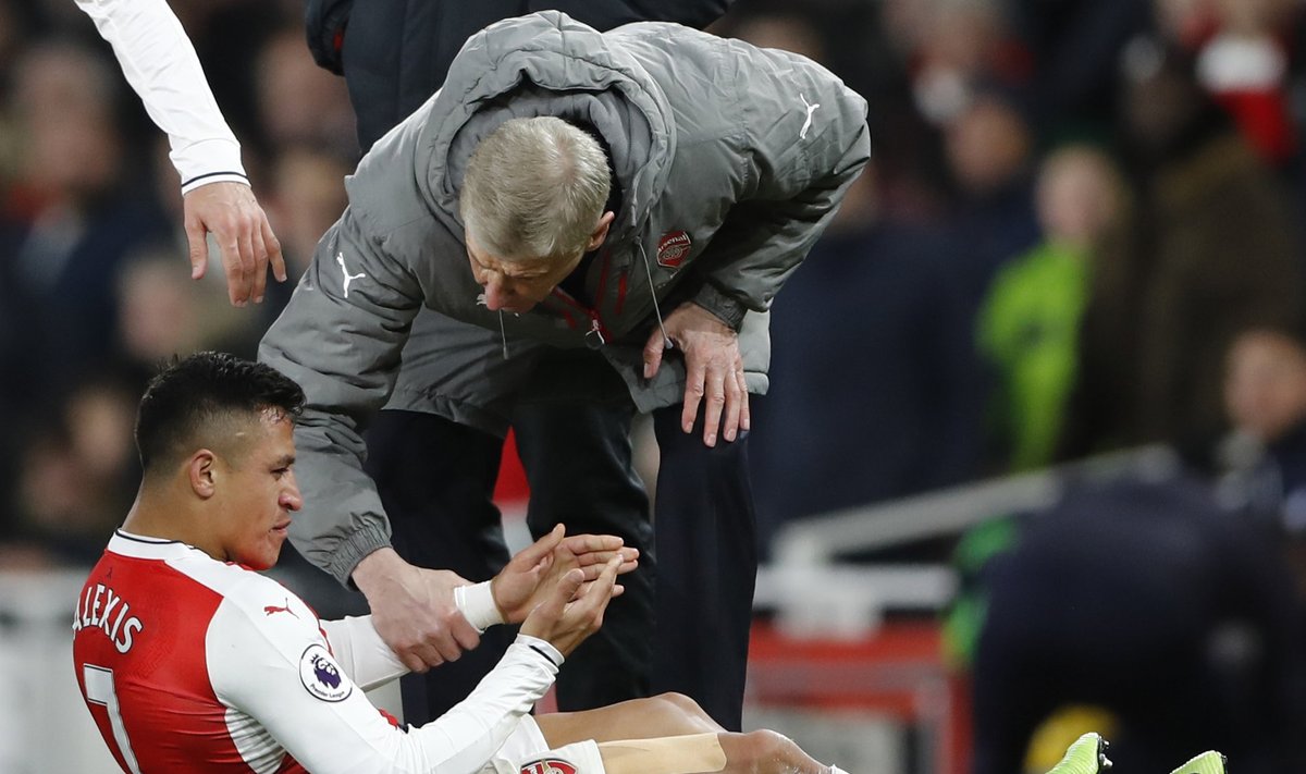 Arsenal manager Arsene Wenger speaks with Alexis Sanchez as he sits injured