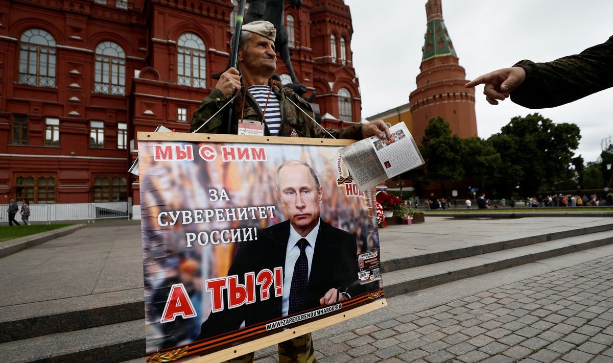 TEMAGA, AGA MITTE KAUAKS: Vene mees hoiab Kremli ees Putinit toetavat plakatit. Ta on ilmselt Venemaal vähemusse jäämas.