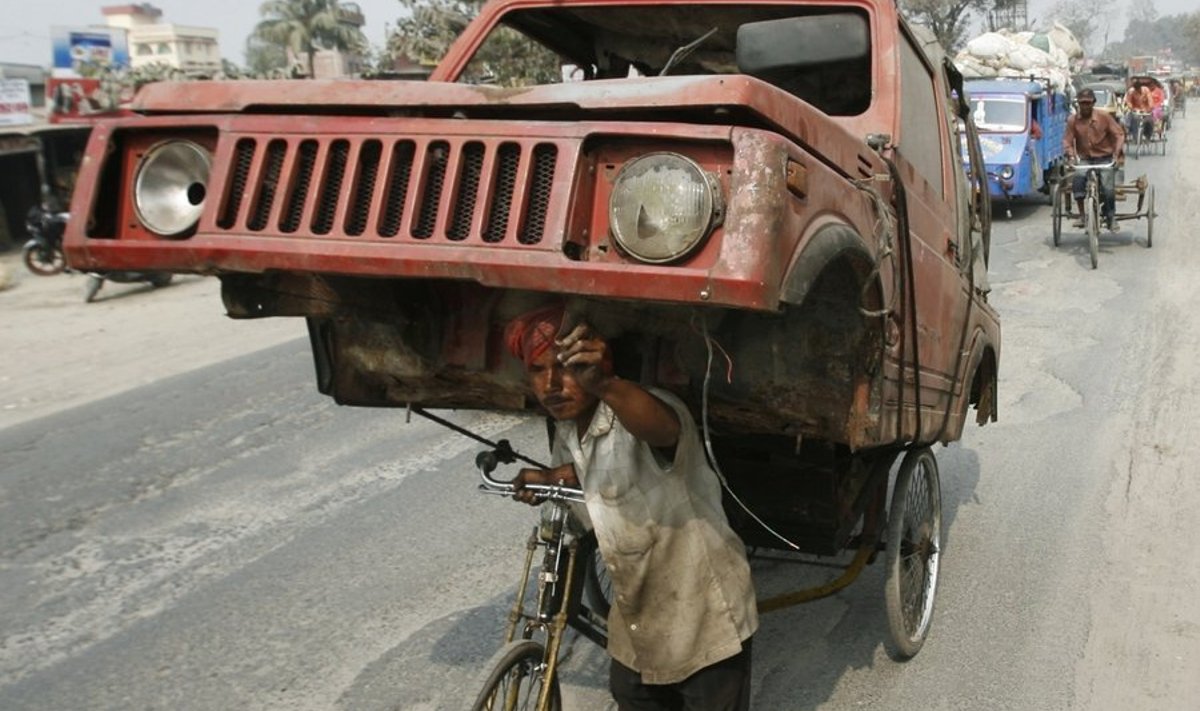 A cycle-rickshaw puller moves the wreckage of a car to a scrap yard in the eastern Indian city of Siliguri February 2, 2010. REUTERS/Rupak De Chowdhuri (INDIA - Tags: TRANSPORT SOCIETY)