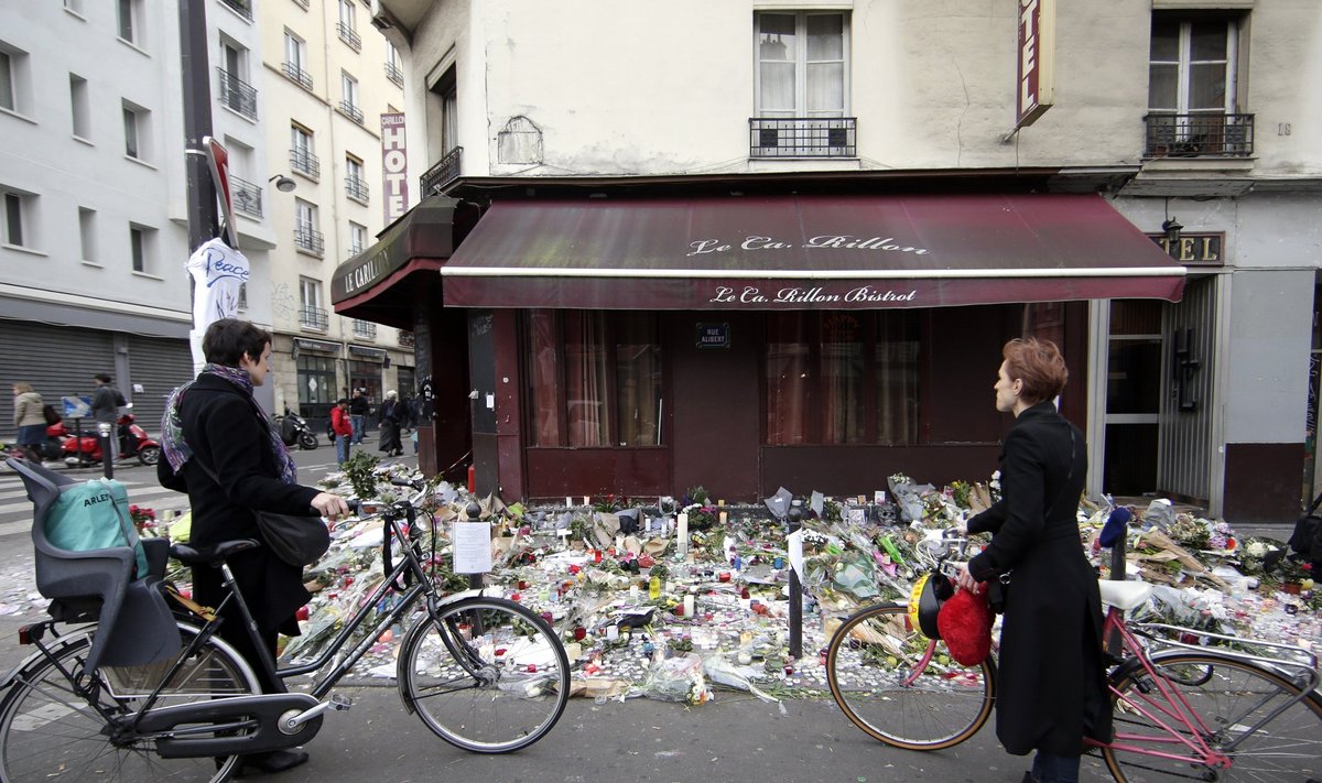 Two people with bicycles stop to pay tribute to victims outside Le Carillon restaurant, one of the attack sites in Paris