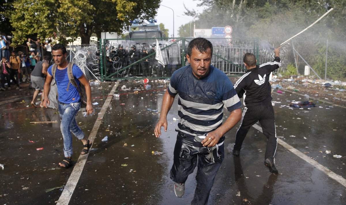Migrants run as Hungarian riot police fires tear gas and water cannon at the border crossing with Serbia in Roszke
