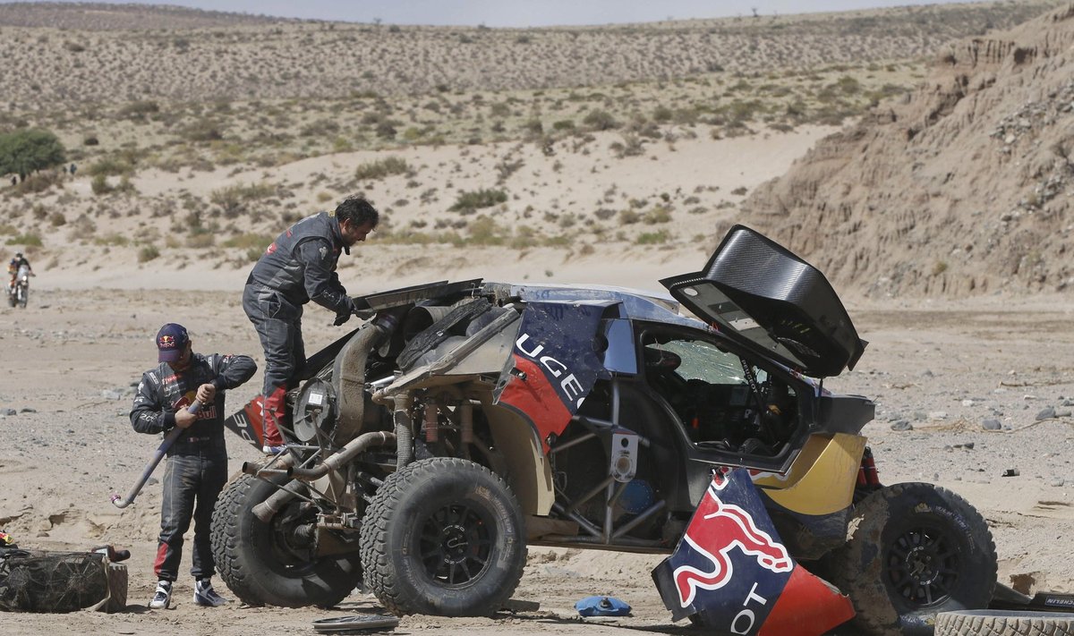 Loeb of France and co-pilot Elena work on their car after an accident which turned the car over during the eighth stage in the Dakar Rally 2016 near Belen