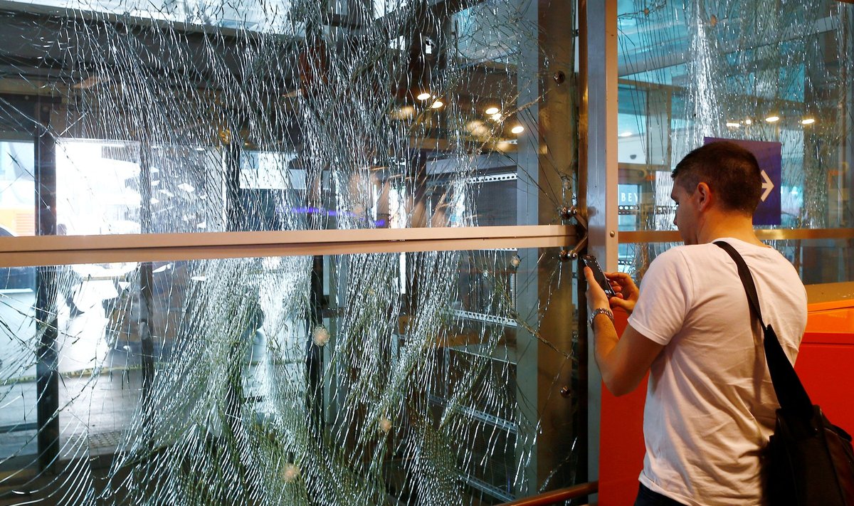 A man takes pictures of a broken window at Turkey's largest airport, Istanbul Ataturk