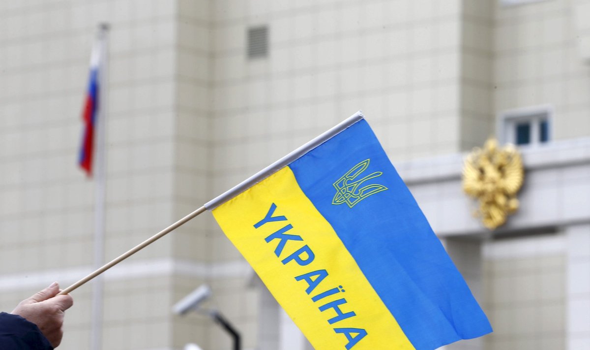 Man holds a Ukrainian national flag during a protest in front of Russian embassy demanding the liberation of Ukrainian army pilot Nadezhda Savchenko by Russia, in Minsk