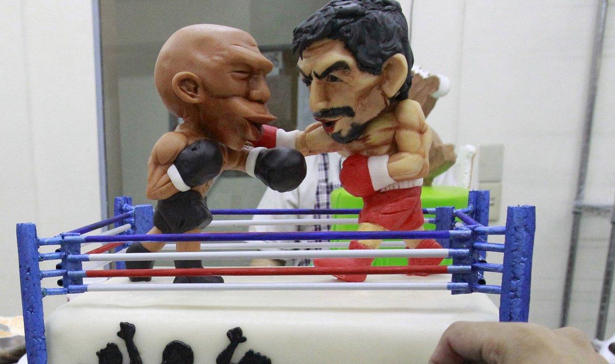 A cake decorator places details on a two-layer cake featuring fondant caricatures of boxers Manny Pacquiao (R) of the Philippines and Floyd Mayweather of the U.S. inside a boxing ring in Manila