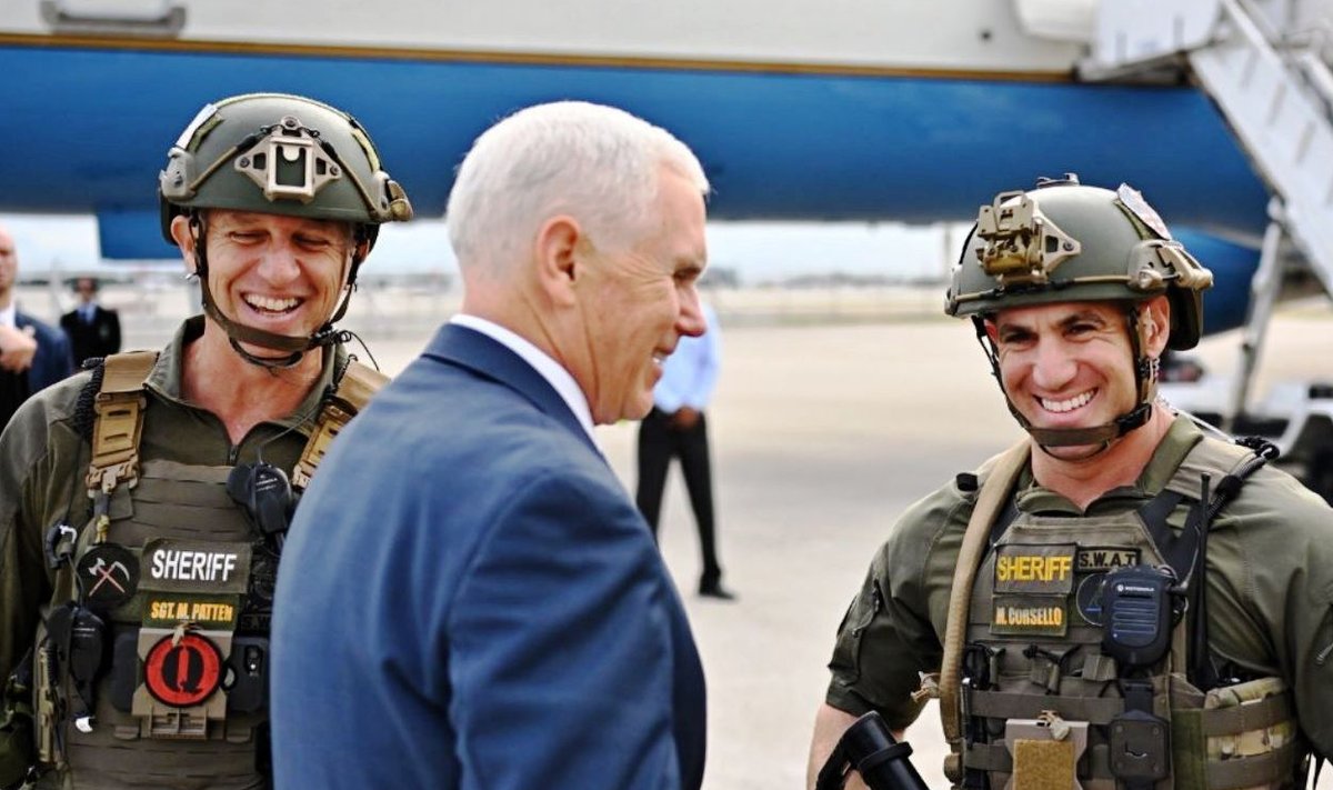 QANONI POLITSEI: Trumpi administratsiooni asepresident Mike Pence koos Florida osariigi Browardi maakonna politsei kiirreageerijatega. Vasakpoolse politseiniku rinnal olevat Q-tähte kannavad QAnoni jüngrid.