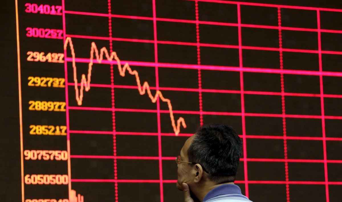 An investor looks at an electronic board showing stock information of Shanghai Stock Exchange Composite Index in Beijing