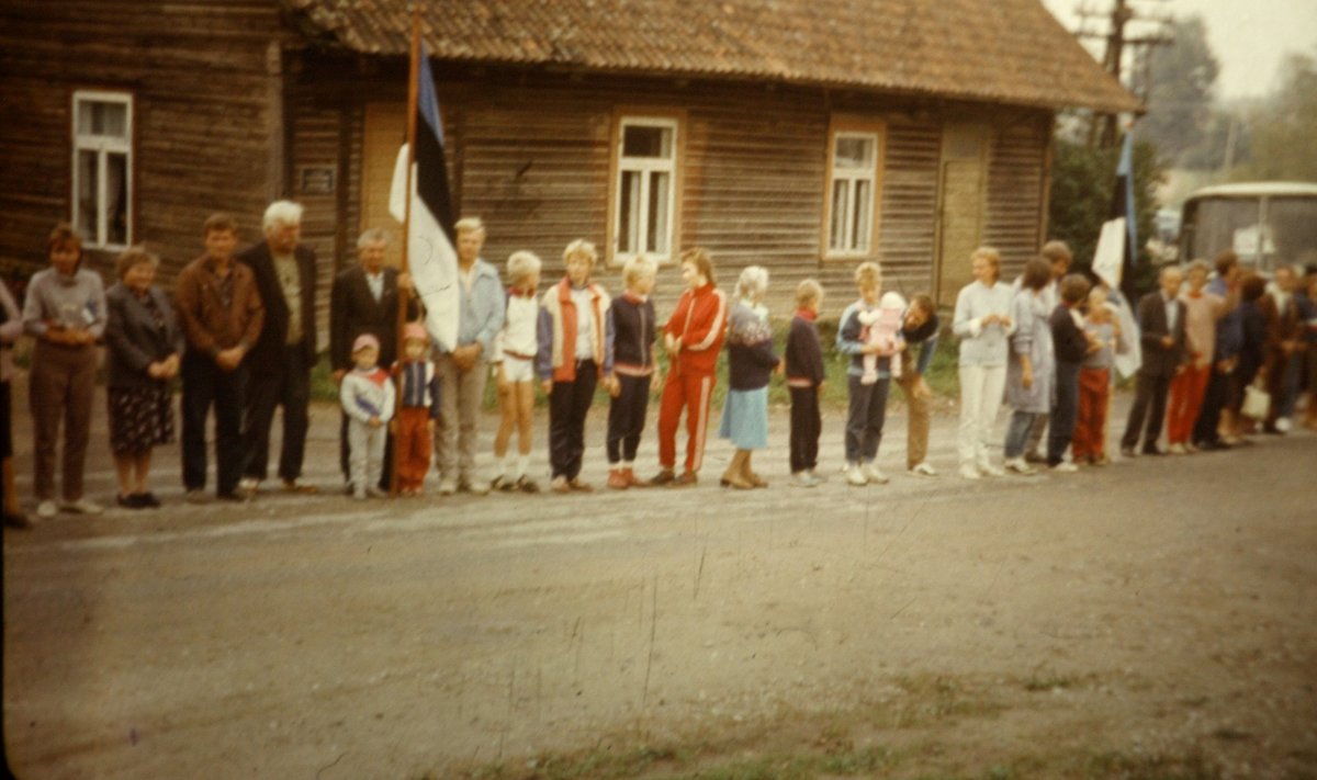 Paarikümnest inimesest koosnev suguvõsa seisab Lilli külas oma maja vastas keset maanteed. Lippu hoiab Heikki Lenk koos lastelastega. Tema kõrval seisavad pojad ja abikaasa. Reas on eri vanuses lapsi, kõik praeguseks 30 aastat vanemad. Noorim oli toona viiekuune.