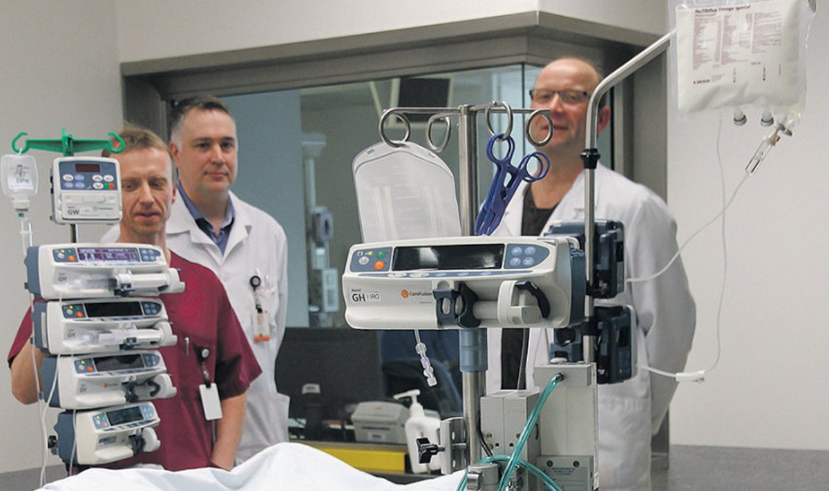 Dr Indrek Rätsep, dr Peeter Põld ja dr Valdo Toome ECMO-l oleva patsiendi juures. Pildilt on näha, et parempoolses voolikus voolab hapnikurikas veri patsiendi südamesse tagasi. 