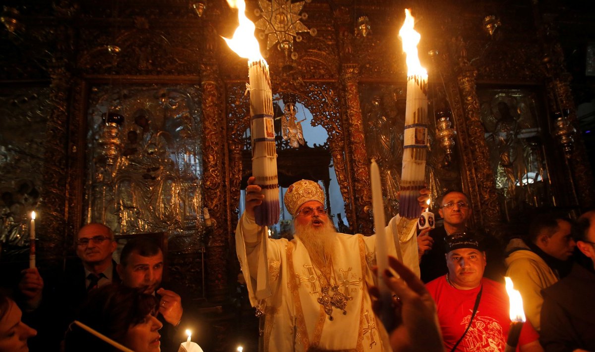 The head of the Greek Orthodox church in Bethlehem Bishop Theofilactos holds candles lit up from 'Holy Fire' after its arrival from Jerusalem's Holy Sepulchre in the Church of the Nativity in the West Bank town of Bethlehem