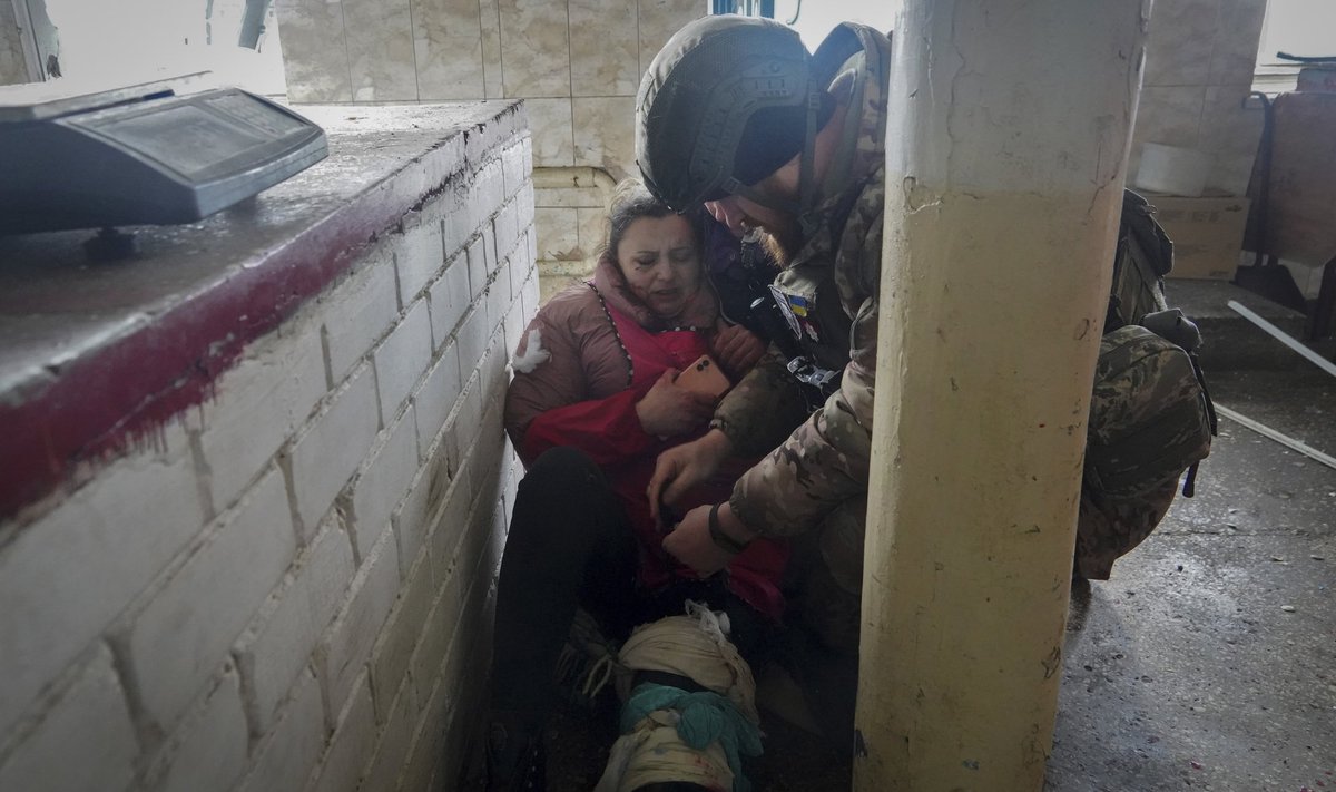 Военнослужащий оказывает первую помощь раненой женщине после обстрела российской артиллерией города Волчанска Харьковской области Украины в пяти километрах от границы с Россией во вторник, 13 февраля.
