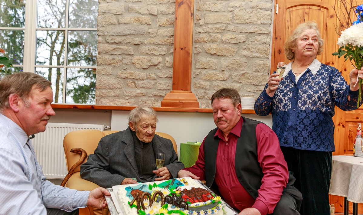 Suurt uhket torti aitavad hoida pojad Toivo (vasakul) ja Tõnu. Tordi kohta jagab selgitusi Tareste külaseltsi eestvedaja Kati Haamer.