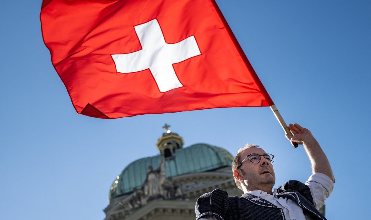 Esineja Šveitsi lipuga riigi parlamendihoone ees.