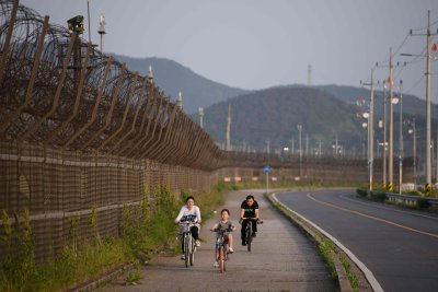 Jalgratastel pere demilitariseeritud tsooni okastraataia lähedal Lõuna-Koreas Ganghwado saarel.