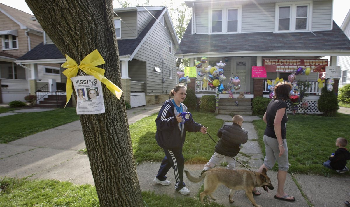 Neighbors walk past missing poster as balloons hang outside the home of Beth Berry in Cleveland