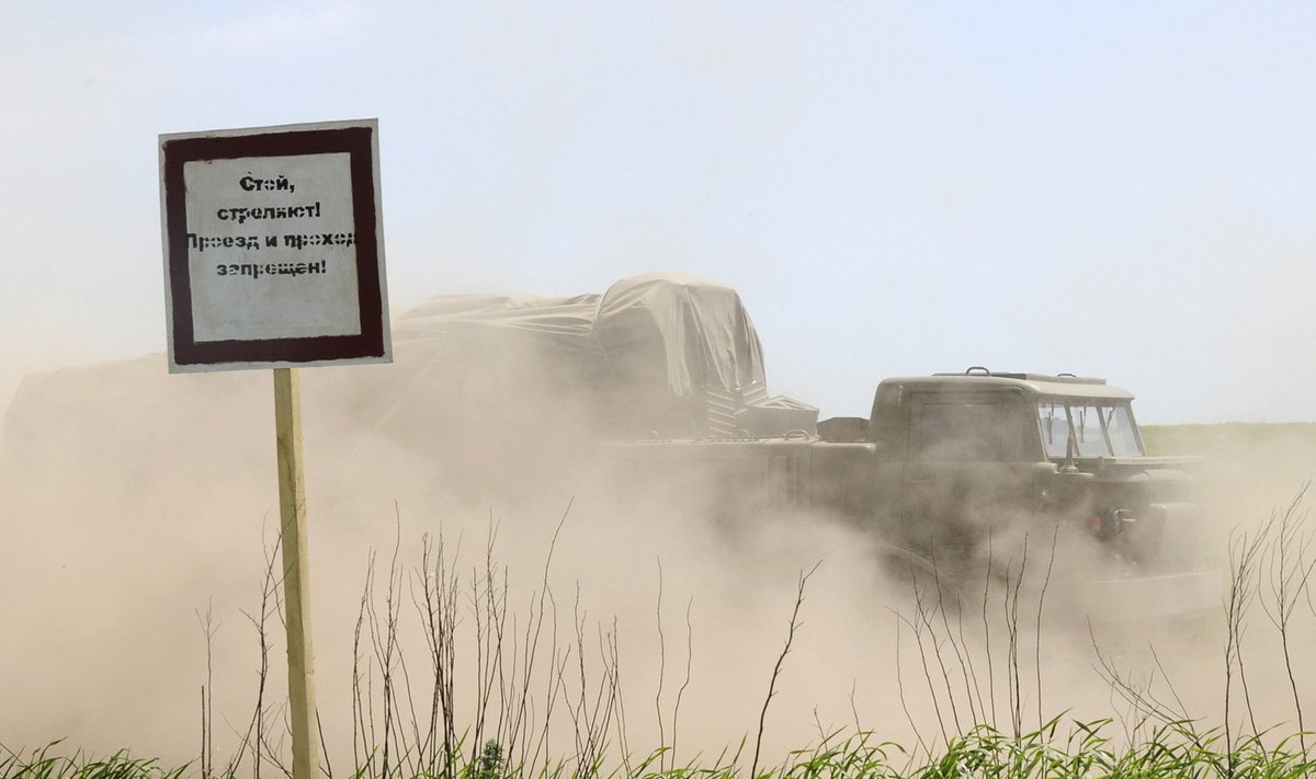 A multiple launch rocket system drives past a sign at the Kuzminsky military training ground near the Russian southern village of Chkalovo in the Rostov region