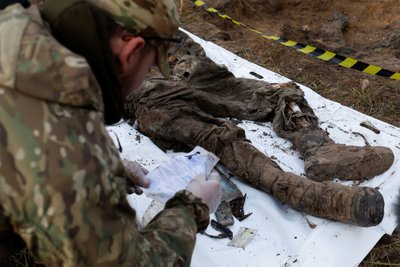HUKKUNU TUVASTAMISEL: Oleksii Jukov kontrollib humanitaarmissiooni käigus välja kaevatud Ukraina sõduri juurest leitud isikutunnistusi.