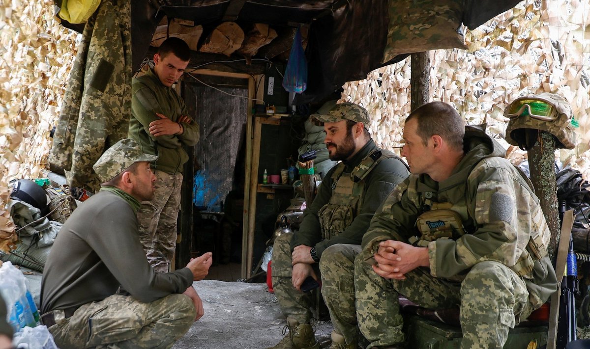 Украинские военнослужащие разговаривают друг с другом возле блиндажа на своей позиции на передовой в Донецкой области.