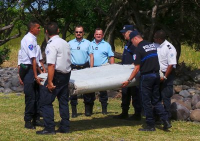 French gendarmes and police carry a large piece of plane debris which was found on the beach in Saint-Andre, on the French Indian Ocean island of La Reunion