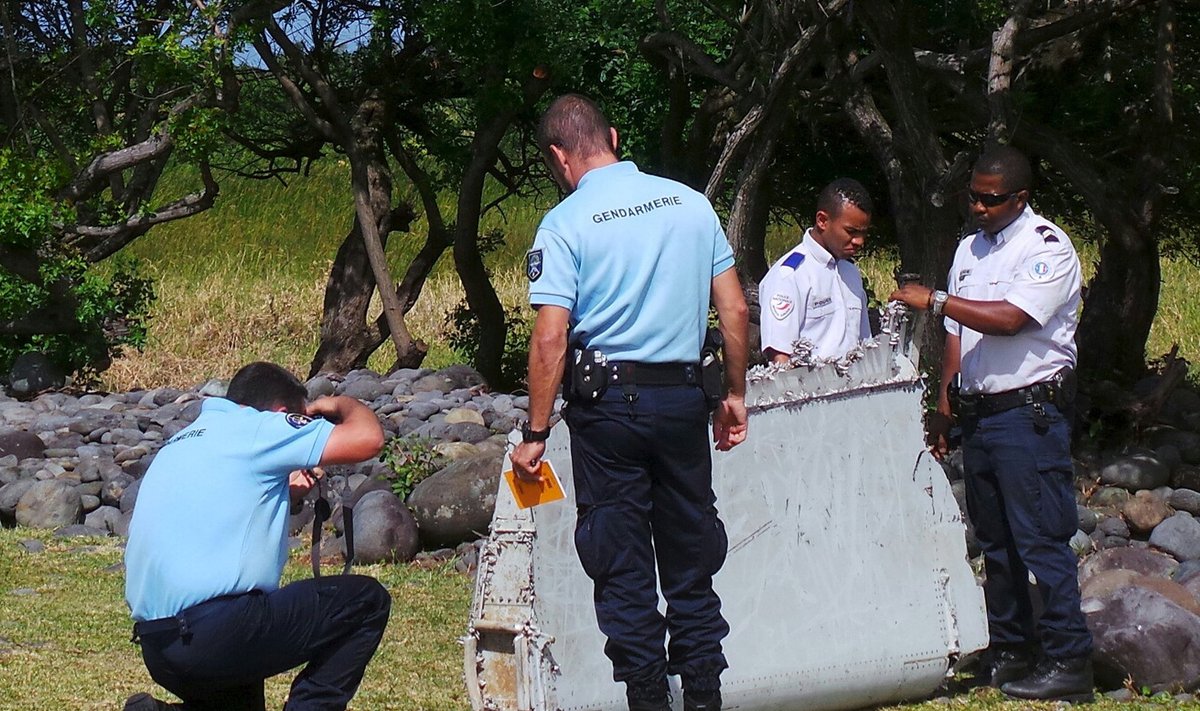 French gendarmes and police inspect a large piece of plane debris which was found on the beach in Saint-Andre, on the French Indian Ocean island of La Reunion