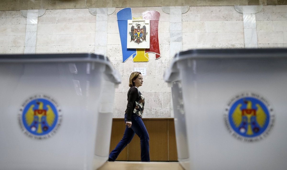 Ballot boxes are seen as a member of a local electoral commission passes by at a polling station in Chisinau